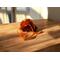 Orange sachet of Irish Twins Potpourri on a wooden surface with warm sunlight casting soft shadows, creating a cozy, inviting atmosphere.